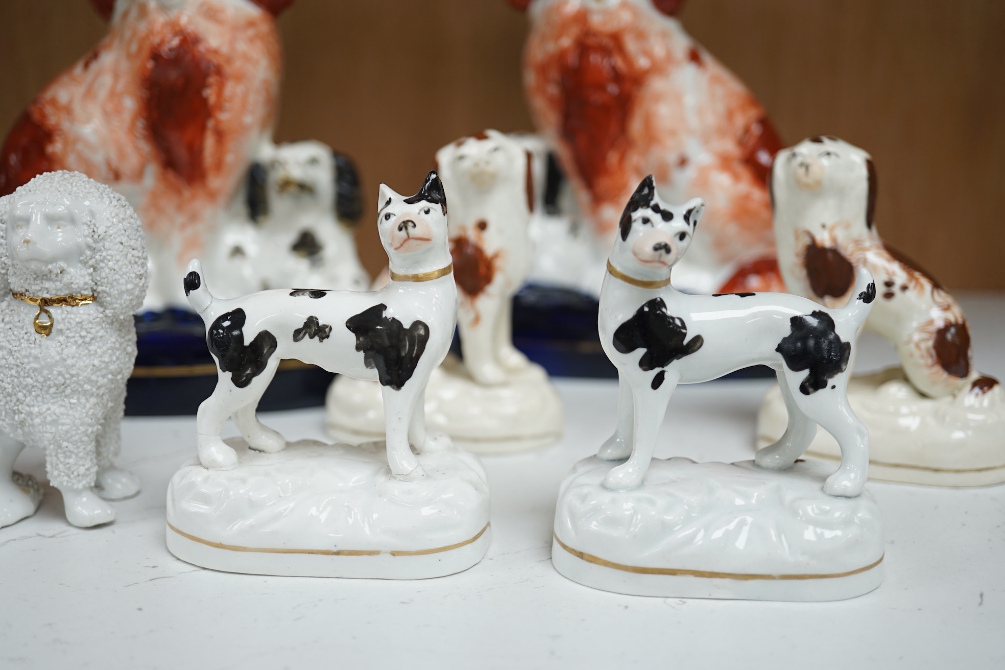 A pair of mid 19th century Staffordshire spaniel and puppy groups, a pair of smaller Staffordshire spaniel figures, and a pair of Staffordshire porcelain figures of standing terriers, c.1835, together with a Continental